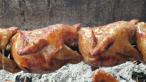Juicy grilled chicken cooks evenly on a rotating charcoal grill, infused with smoky flavor and crispy perfection.