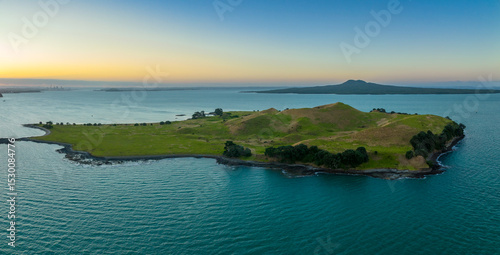 Aerial view of Browns Island (Motukorea) in the Hauraki Gulf, New Zealand, with Auckland city and Rangitoto in the distance at sunrise. photo
