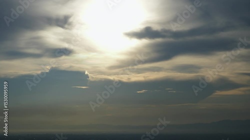 Time-lapse of the glowing sunset fades as it disappears into thick clouds, casting a soft, mysterious light across the sky.