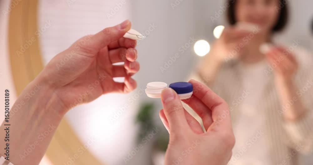 Woman taking contact lens out of case near mirror indoors, closeup Woman taking contact lens out of case near mirror indoors, closeup