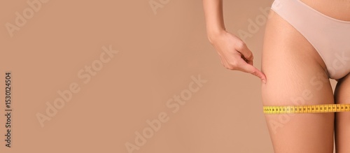 Beautiful young woman with stretch marks on her body and measuring tape against beige background with space for text, closeup