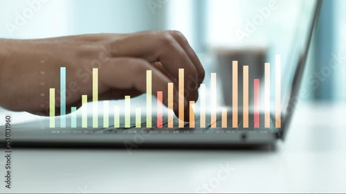 Business hand typing on laptop keyboard with colorful financial bar graph overlay.