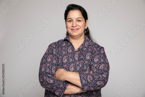 Indian middle age woman wearing white shirt standing over isolated white background happy face smiling with crossed arms looking at camera