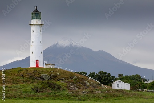 Cape Egmont Lighthouse stands tall on the coast of Pungarehu, Taranaki, New Zealand, guiding ships safely. The iconic landmark is set against the backdrop of Mount Taranaki.