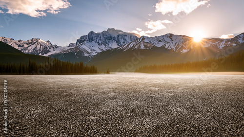The wide asphalt road with no one around is set against the backdrop of snow-capped mountains