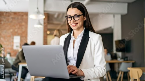 Stylish businesswoman working on laptop with smile in contemporary workspace