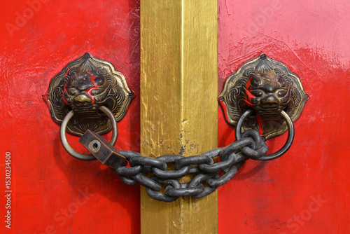 locked traditional chinese door with chain and padlock with lion head door knockers