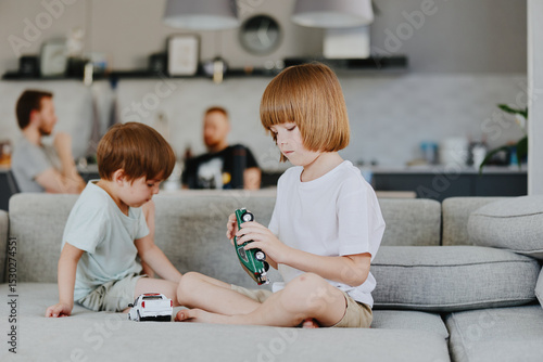 Two playful boys enjoy their time together at home, surrounded by toys, showcasing a fun and relaxed atmosphere in a bright, modern living space.