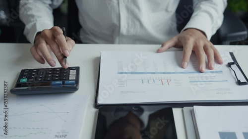 Male Accountant Reviewing Financial Documents with Calculator.