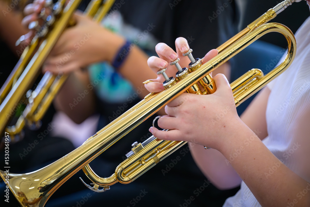 Fototapeta premium A trumpet being played by a youth in the foreground with other trumpets blurred in the background.