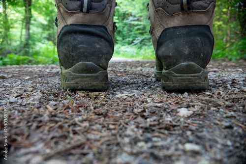 Man stands on forest road woodland shoes. Closeup shot. A pair of brown black boots on a sandy floor. Rear view.