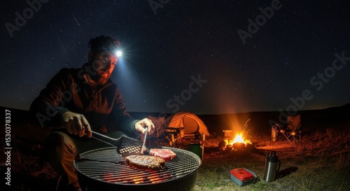 Young caucasian male grilling steak while camping under starry night sky
