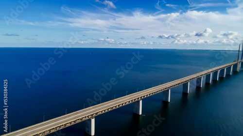 Wallpaper Mural Aerial view of a long highway bridge over a calm, expansive ocean, under a sky with scattered clouds, creating a serene and scenic landscape. Torontodigital.ca