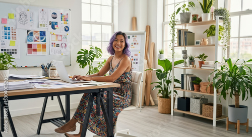 Smiling Woman At Desk In Bright Office With Plants And Laptop Smiling And Working