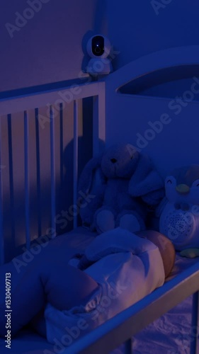 Healthy baby with plushies sleeps in crib under monitor