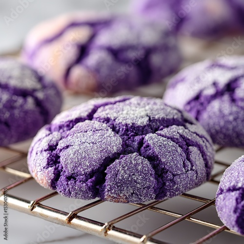 Close up of ube crinkle cookies dusted with powdered sugar on a wire cooling rack surface view
