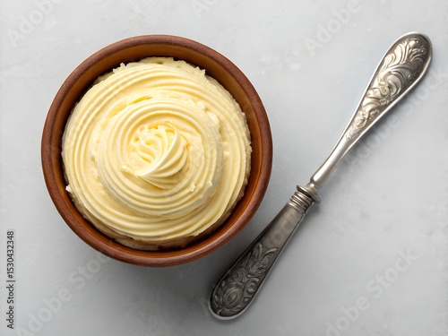 Swirled butter in a brown ceramic bowl with ornate silver butter knife