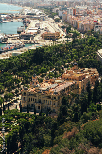 Historic architecture amidst lush greenery with a port city backdrop.