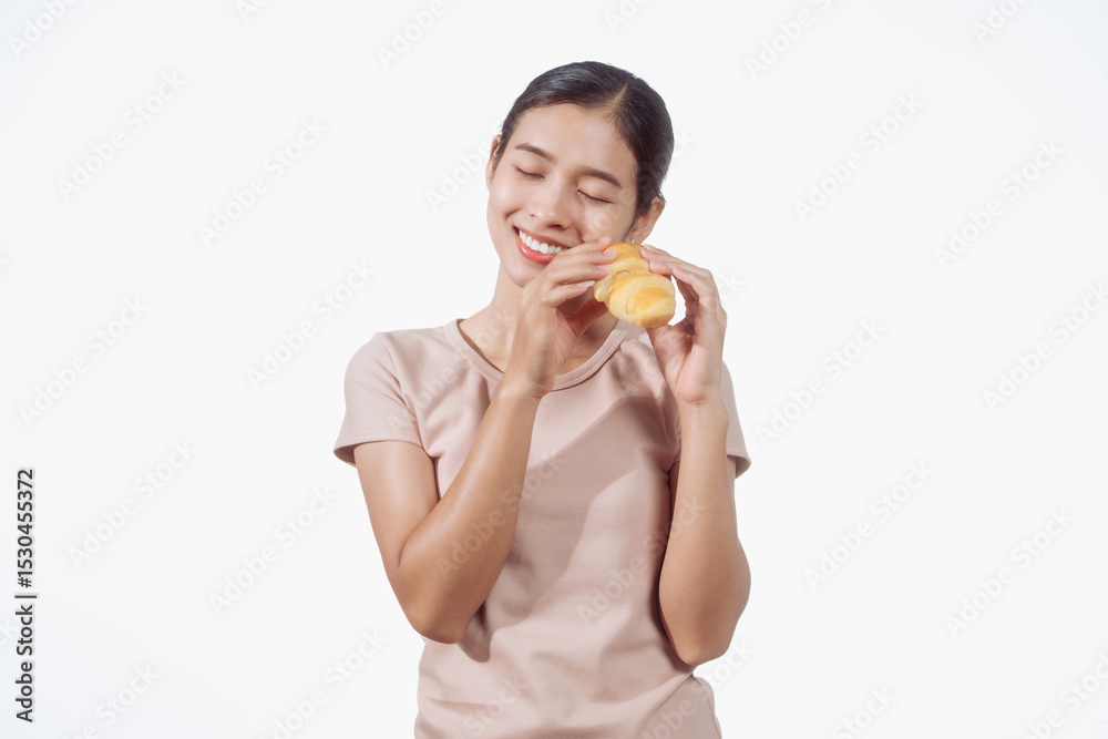 A confident young Asian woman in a light brown shirt stands against a white background, happily holding a delicious croissant in her hand, ready to enjoy a fresh and tasty pastry snack. A confident young Asian woman in a light brown shirt stands against a white background, happily holding a delicious croissant in her hand, ready to enjoy a fresh and tasty pastry snack.