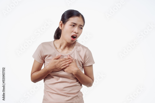 Confident young Asian woman in light brown shirt stands against white background, chest pain. Possible causes include heart, breast, lung, digestive, or musculoskeletal, requiring careful assessment.