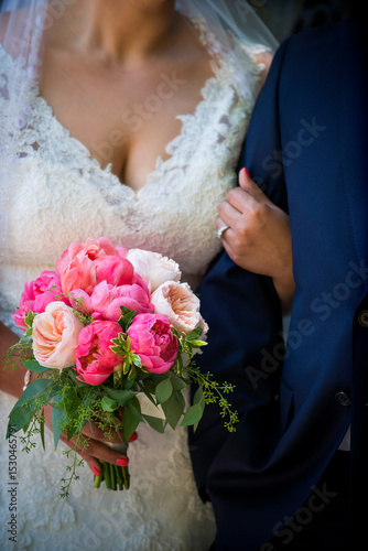 Bride Holding Pink Bouquet Arm-in-Arm with Groom in Navy Suit photo