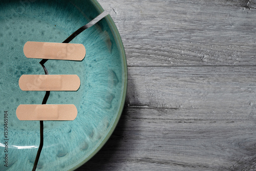 Fototapeta Cracked ceramic plate with band-aids.