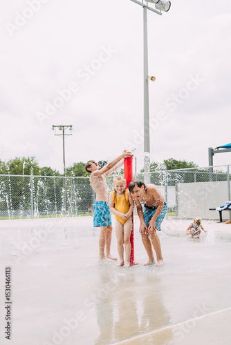 Big kids playing at splash pad in water fountain in summertime