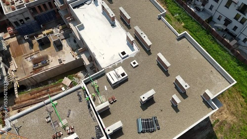 Aerial view of residential complex construction with crane over rooftops, Workers and materials visible on upper levels of multistory concrete structure