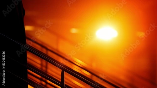 Graduation ceremony captures a graduate ascending stairs against a vibrant sunset backdrop