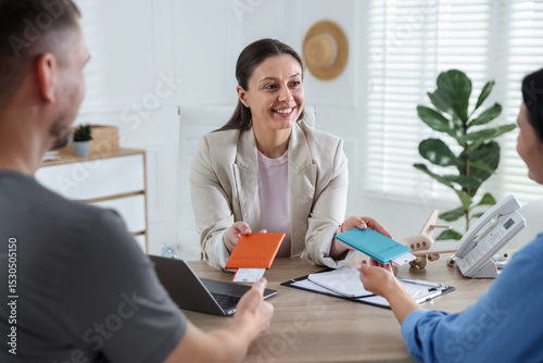 Happy couple planning vacation with travel agent at wooden table in office