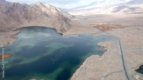 Drone view of Karakul Lake‌ on sunny cloudy day in Tashkurgan County, Kashgar, Southern Xinjiang, China. Aerial landscape of landmark on Pamir plateau, 4k real time panning footage, travel concept