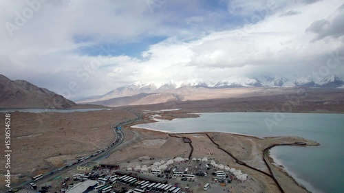 Drone view of Karakul Lake‌ on sunny cloudy day in Tashkurgan County, Kashgar, Southern Xinjiang, China. Aerial landscape of landmark on Pamir plateau, 4k real time footage, travel concept photo