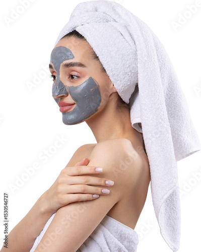 A woman with a gray clay cosmetic mask in a white towel on her head on a white background.