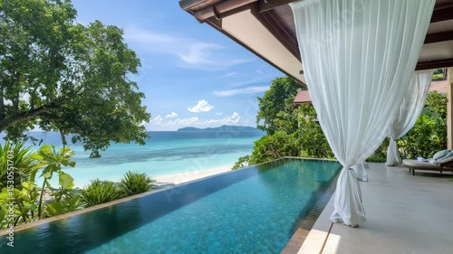A luxurious beachfront villa with infinity pool, white curtains, and stunning ocean views, surrounded by lush tropical greenery.
