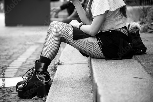 Closeup of legs of gothic girl wearing sexy stockings and black boots standing in the street