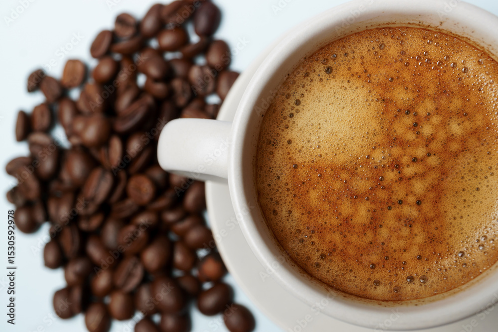 Fototapeta premium Freshly brewed coffee with crema in a white cup, accompanied by roasted coffee beans, creating a cozy and inviting scene