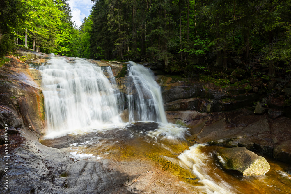Obraz premium Mumlava Waterfall cascading through rocks and lush forest in Harrachov, Czechia