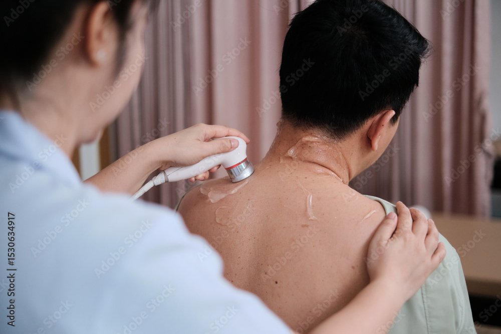 Male Asian patient is treated for healthy recovery, gel ultrasound for shoulder pain relief by female physical muscle doctor, passive medical therapy at spa clinic, and wellness massaging healthcare. Male Asian patient is treated for healthy recovery, gel ultrasound for shoulder pain relief by female physical muscle doctor, passive medical therapy at spa clinic, and wellness massaging healthcare.