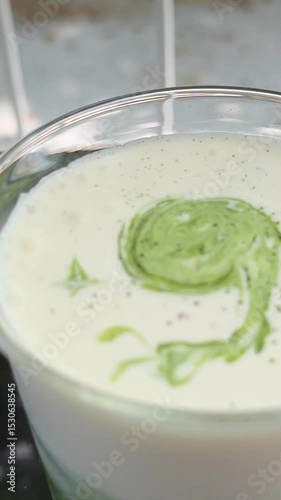 Slow motion of barista pouring milk over creating Matcha latte art. High quality 4k footage
