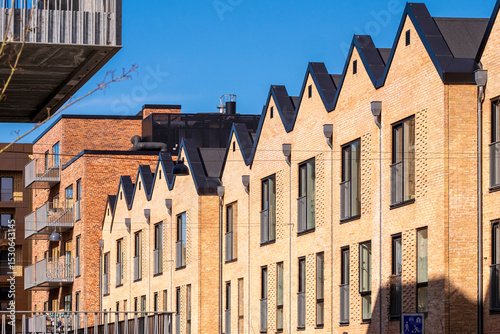 Contemporary brick housing in Ørestad, Copenhagen with geometric roofline and shadow play, architectural design and real estate concept for business visuals photo