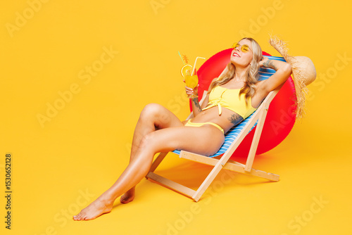 Full body young beautiful sexy woman she wear bikini swimsuit rest near hotel pool lies on deckchair drink cocktail close eyes isolated on plain yellow background. Summer vacation sea sun tan concept.