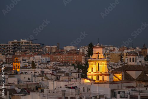 A view of a prominant church, set amoungst the buildings of Seville, Andalusai, Spain, lit up at night photo