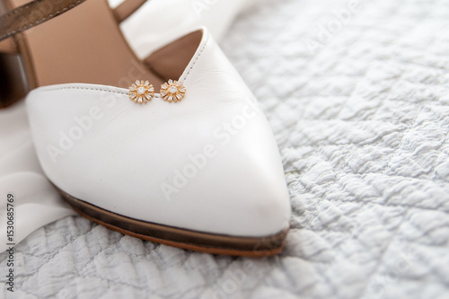 Pendientes de oro puestos en un zapato de novia como bodegón en las fotos de boda