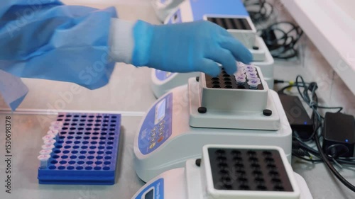 A lab technician places test tubes of liquid on a DNA analyzer