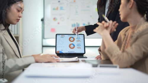 Team analyzing financial data on laptop in office meeting