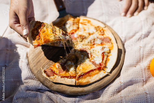 Family enjoys leisure picnic with people sharing delicious cheese pizza on wooden board outdoors, capturing concept of togetherness and casual dining in relaxed setting