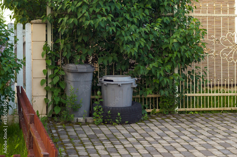 Naklejka premium Two garbage bins at fence.Periodic garbage collection.