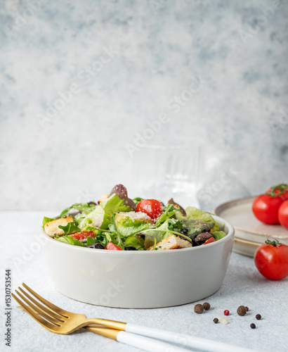 Vegetarian salad with lettuce, tomatoes, croutons, olives and parmesan cheese in a bowl