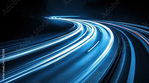 Winding highway at night, illuminated by car lights.