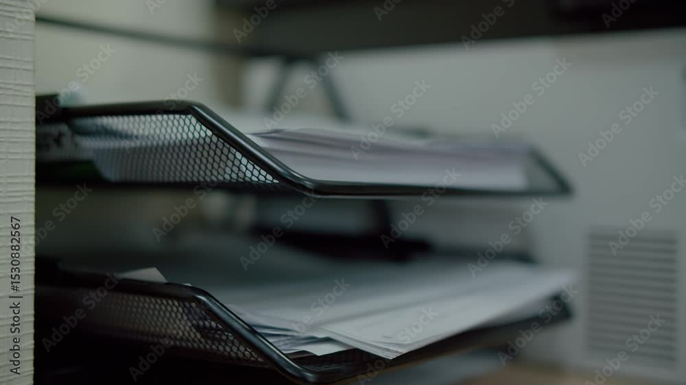 Hand placing documents in office paper tray